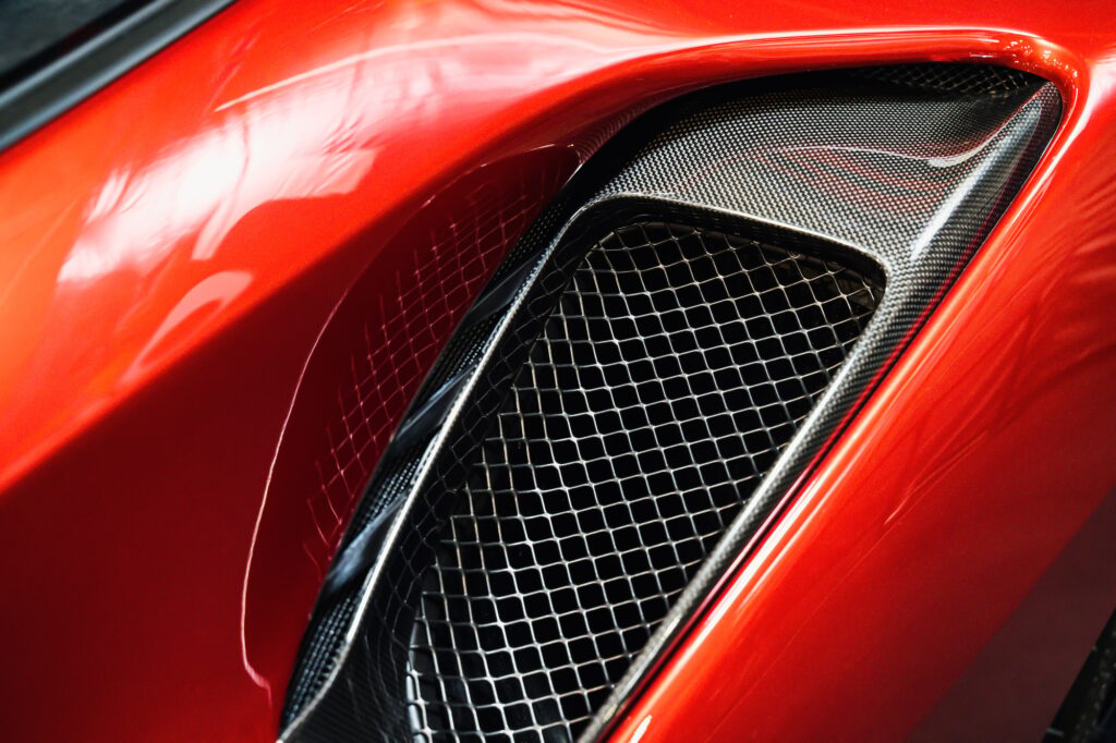 detail of sport car with red metal hood and black air flow intake ornament